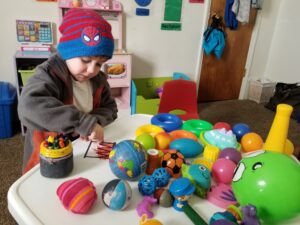 un niño pequeño sentado en una mesa cubierta con bolas de diferentes tamaños